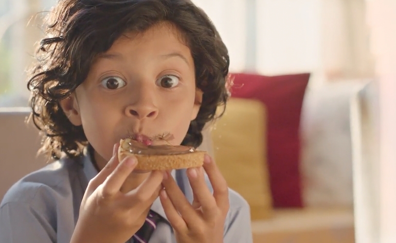 Boy enjoying HERSHEY'S SPREADS on a bread 